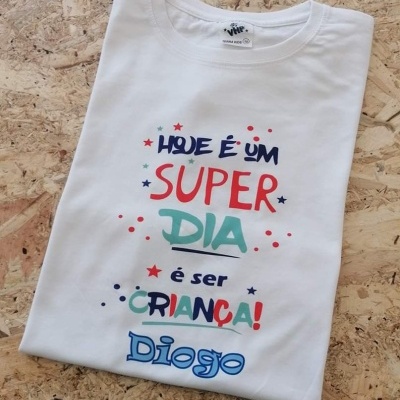T-shirt branca com texto colorido e decoração de estrelas e pontos em madeira clara