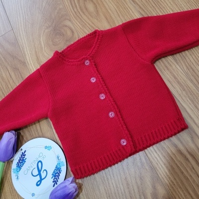 Camisola de malha vermelha com botões, flores lilases artificiais e cartão branco