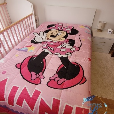 Edredão cor-de-rosa com personagem Minnie Mouse em cama branca num quarto infantil