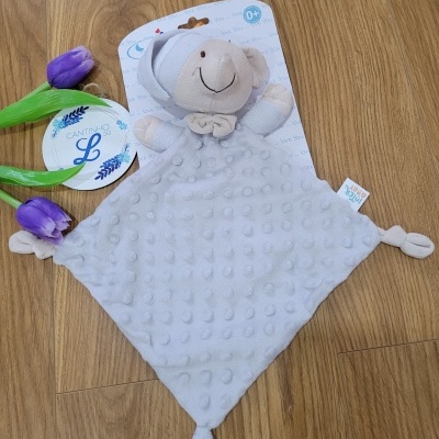 Brinquedo de pelúcia cinzento claro com cabeça de ursinho, textura de bolinhas, e tulipas roxas sobre chão de madeira