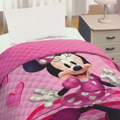 Cobertor rosa estampado com Minnie Mouse sobre cama branca com almofada e mesa de cabeceira cinza