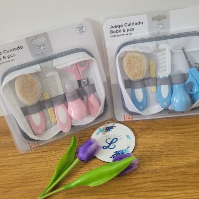 Conjuntos de cuidados para bebé de 6 peças, rosa e azul, em embalagem plástica sobre superfície de madeira com duas tulipas roxas