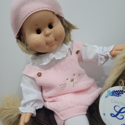 Boneca vestida de rosa sentada numa cadeira de pelúcia