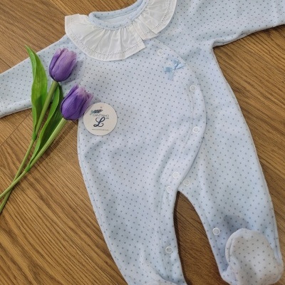 Macacão de bebé azul-claro com colarinho branco e pequenas flores roxas ao lado