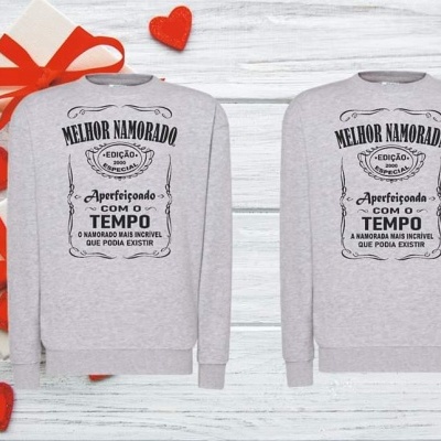Sweatshirts cinzentos com texto 'MELHOR NAMORADO EDIÇÃO APERFEIÇOADA COM O TEMPO' em fundo com presentes e corações vermelhos.