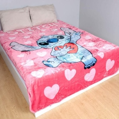 Cobertor rosa com estampa Stitch e corações numa cama branca