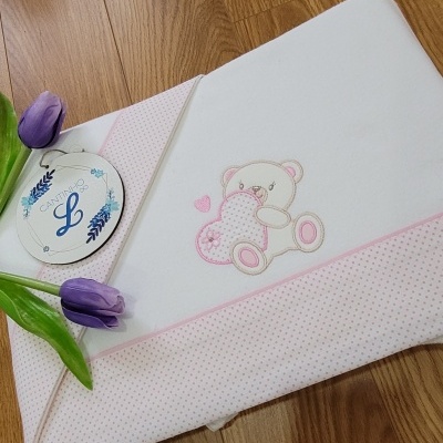Toalha de banho branca para bebé com bordado de ursinho e detalhes cor-de-rosa junto a tulipas roxas e etiqueta
