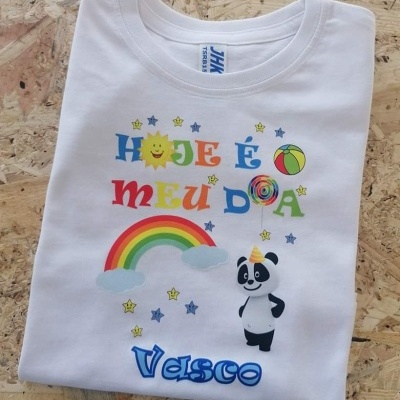 T-shirt branca com estampagem colorida feliz e um panda sobre superfície de madeira.