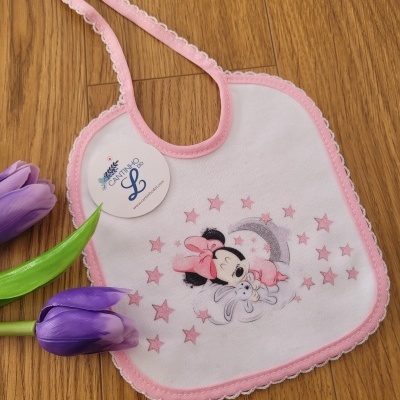 Babete rosa e branco com imagem da Minnie e coelho, em chão de madeira com tulipas roxas