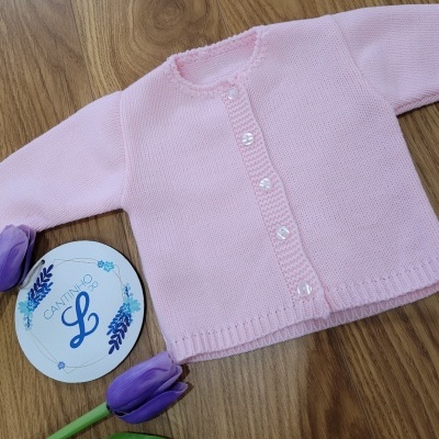 Casaco rosa de malha para bebé com botões e etiqueta redonda com texto ao lado