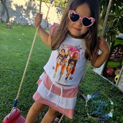 Menina jovem com vestido branco e rosa e óculos de sol rosa em baloiço num jardim
