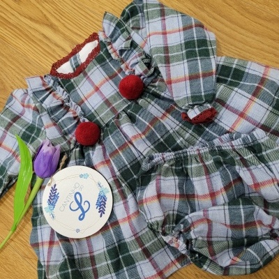 Conjunto de roupa infantil aos quadrados verde, branco, vermelho e cinza com pompons vermelhos