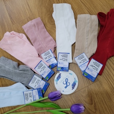 Conjunto de meias coloridas com etiquetas sobre piso de madeira com tulipas roxas e cartão decorativo