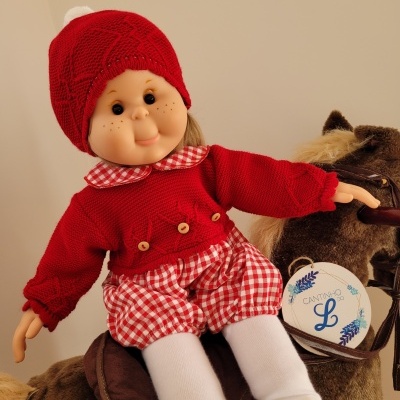 Boneca com roupa vermelha sentada num cavalo de brinquedo castanho