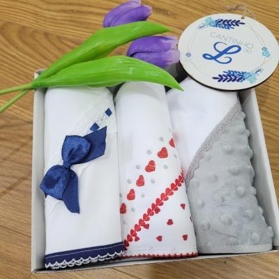 Conjunto de três panos de copa decorativos em caixa com etiqueta e flores artificiais roxas.