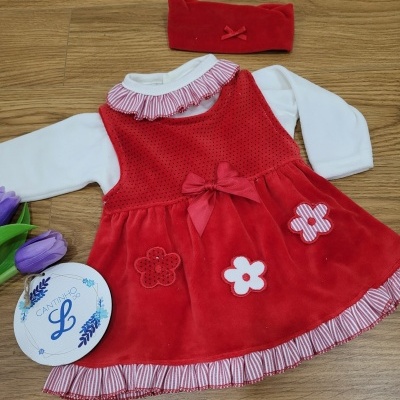 Vestido vermelho de bebé com flores e laço, banda de cabeça vermelha e roupa branca de manga comprida, ao lado de flores roxas e caixa redonda branca
