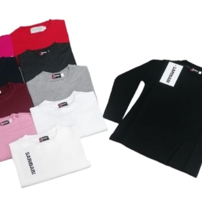 Camisolas de manga comprida para crianças em várias cores empilhadas e uma aberta de cor preta com etiquetas visíveis e tamanhos indicados.