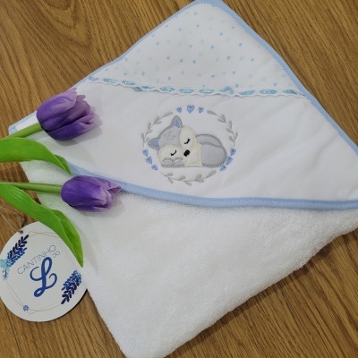 Toalha de bebé branca com capuz azul e bordado de cão, com flores roxas e etiqueta CANTINHO