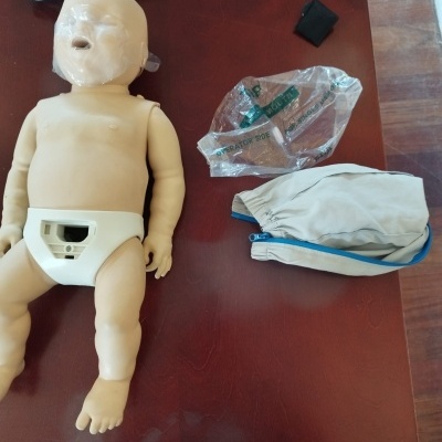 Boneco de treino de primeiros socorros com acessórios sobre superfície castanha