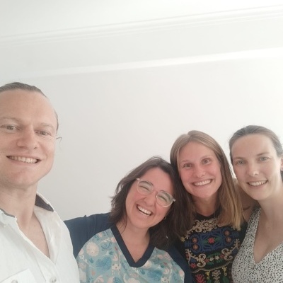 Quatro pessoas sorridentes em ambiente interior com paredes brancas