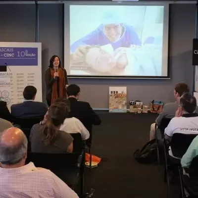 Sala de conferências com público assistindo apresentação em ecrã com banners DNA CASCAIS