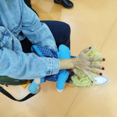 Mão com unhas vermelhas, casaco de ganga e sapato branco, pessoa sentada em chão castanho.