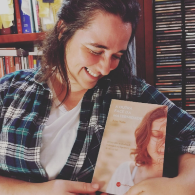 Mulher segurando o livro 'A OUTRA FACE DA MATERNIDADE' de Ana Vale
