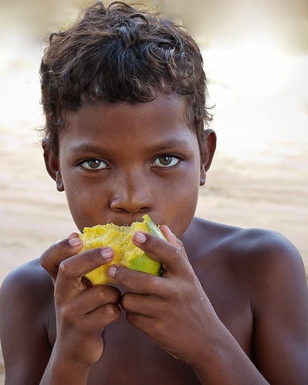 Criança a comer fruta amarela ao ar livre