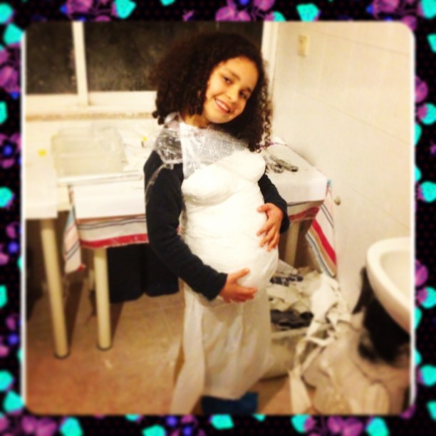 Criança com fantasia que simula gravidez numa cozinha