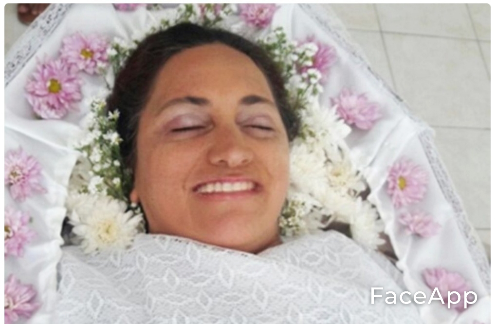 Pessoa deitada coberta por tecido branco e flores ao redor