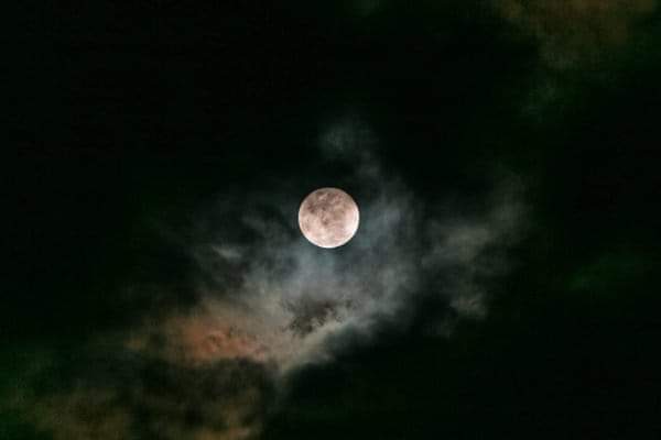 Lua cheia no céu noturno com nuvens escuras
