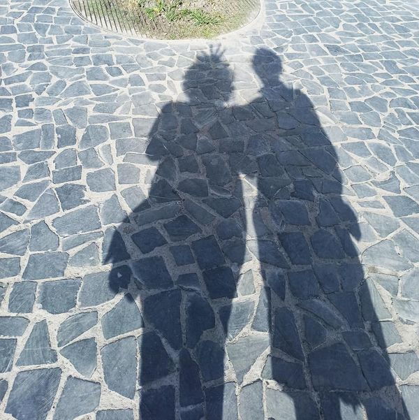 Sombras de duas pessoas numa calçada de pedra