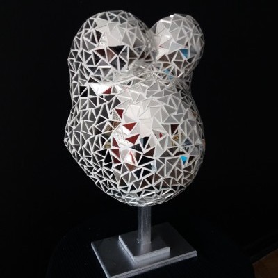 Escultura decorativa metálica prateada com padrão triangular em base cinza