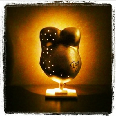 Escultura de corpo feminino preto com pontos brancos numa base iluminada