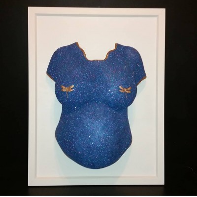 Objeto decorativo em forma de torso feminino azul cintilante com dragões dourados em moldura branca.