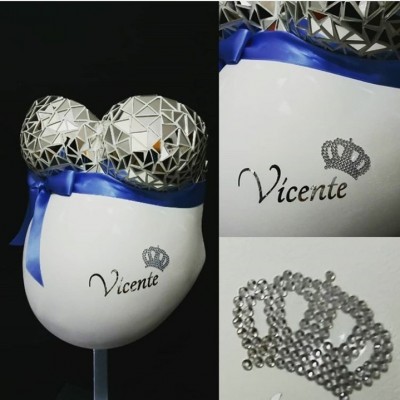 Escultura de barriga de gravidez decorada com padrão geométrico prateado e laço azul