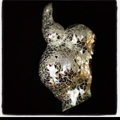 Escultura prateada de espelhos triangulares facetados sobre fundo preto