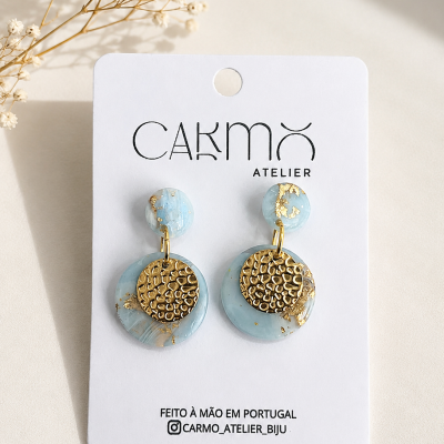 Brincos pendentes azuis com detalhes dourados em cartão branco