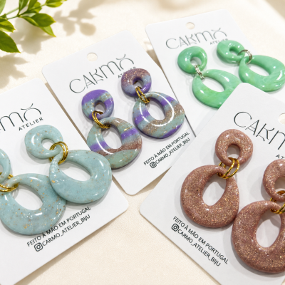 Quatro pares de brincos em resina colorida brilhante em cartões de marca Carmo Atelier.