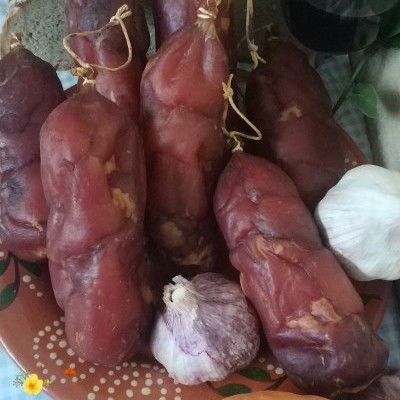 Salames curados vermelhos com alho, pão, vinho tinto e abóbora numa mesa