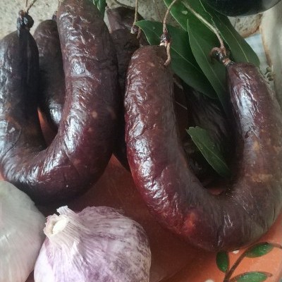 Chouriços, alhos, pão integral e copo de vinho tinto num prato decorativo