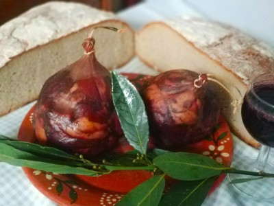 Enchidos, pão rústico, taça de vinho e folhas verdes em prato decorativo