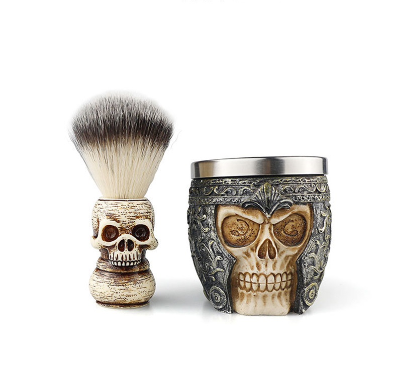 Conjunto de acessórios de barbear com design de caveira, incluindo pincel e recipiente decorado.