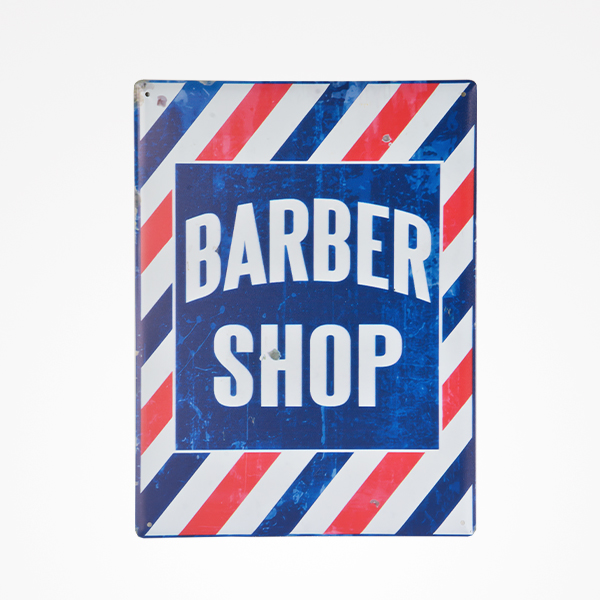 Placa metálica retangular com texto BARBER SHOP e padrão de riscas azuis, vermelhas e brancas