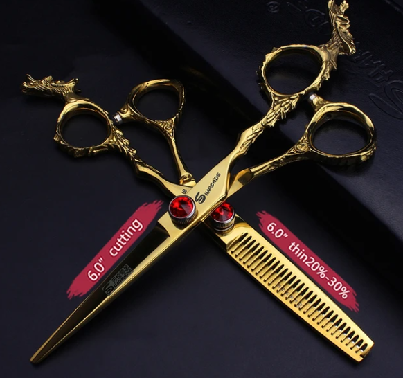 Conjunto de tesouras douradas com detalhes em forma de cabeça de veado e pedras vermelhas.