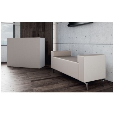 Sofá bege claro com pernas metálicas numa sala com chão de madeira escura e parede de cimento