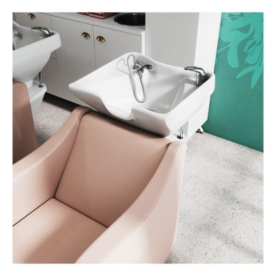 Cadeira de salão rosa claro com lavatório de cerâmica branco e torneira