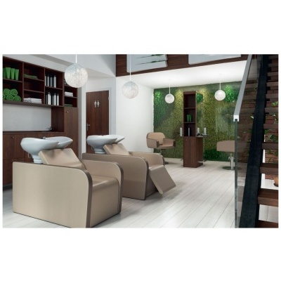 Sala de cabeleireiro com cadeiras beige e lava-cabeças branco, estantes em madeira e parede verde de plantas