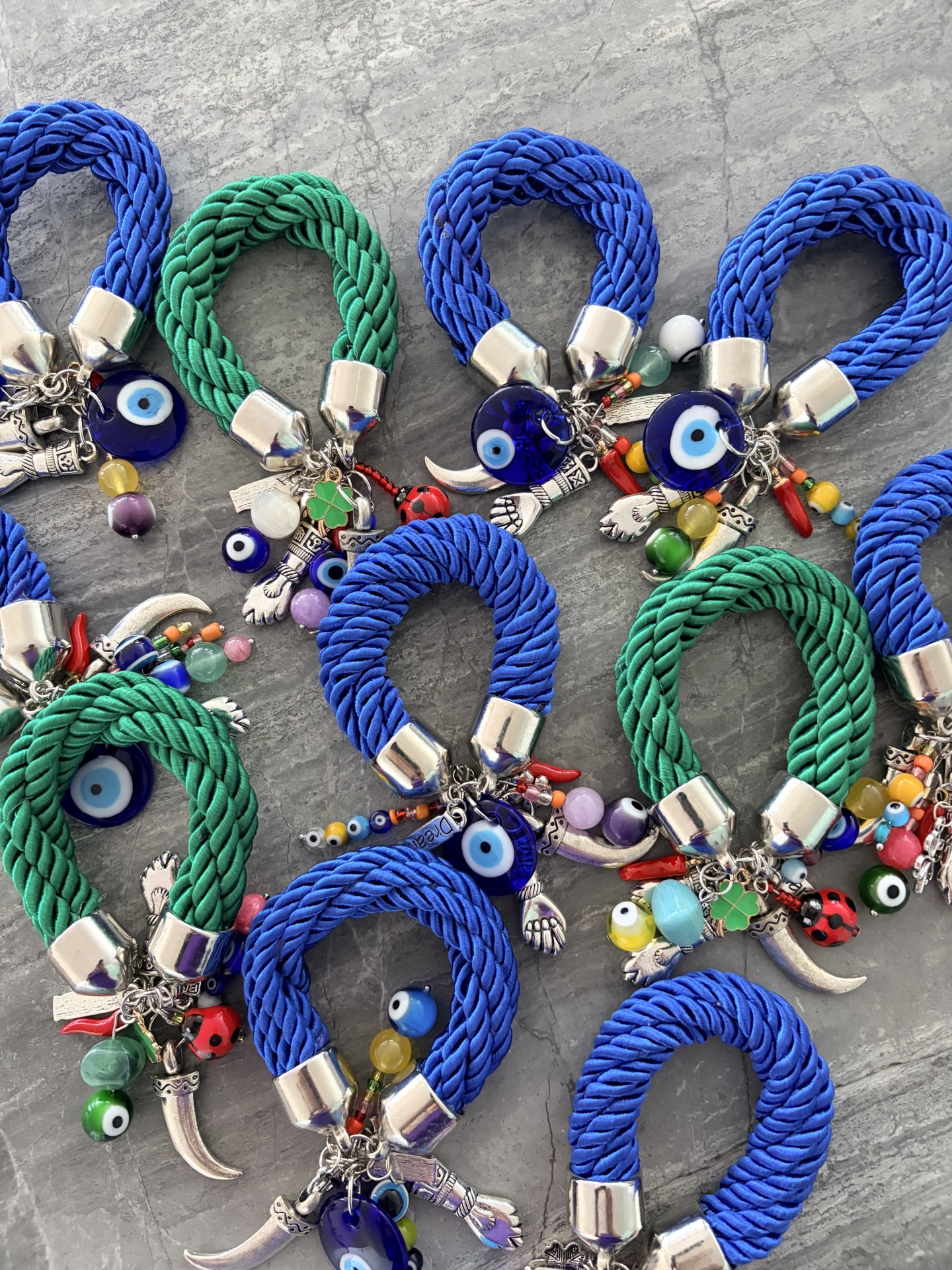 Pulseiras trançadas azuis e verdes com pendentes coloridos e olhos turcos.