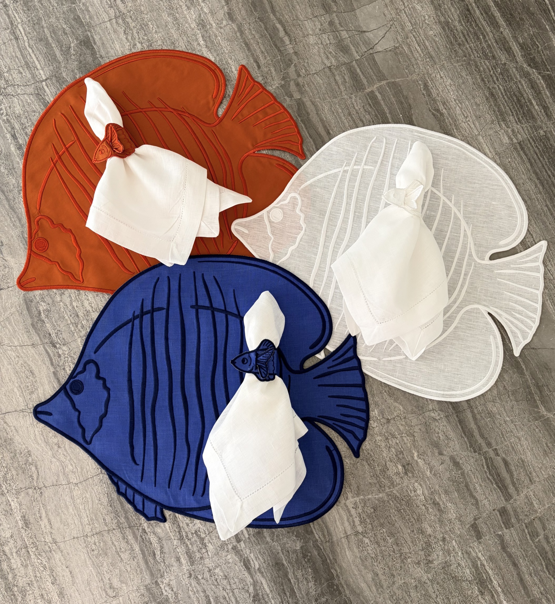 Suportes de pratos em forma de peixe com guardanapos brancos enrolados